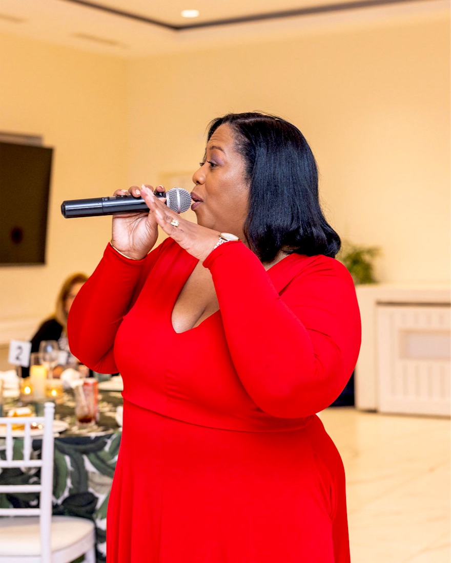 Queen B singing in red at a private dinner