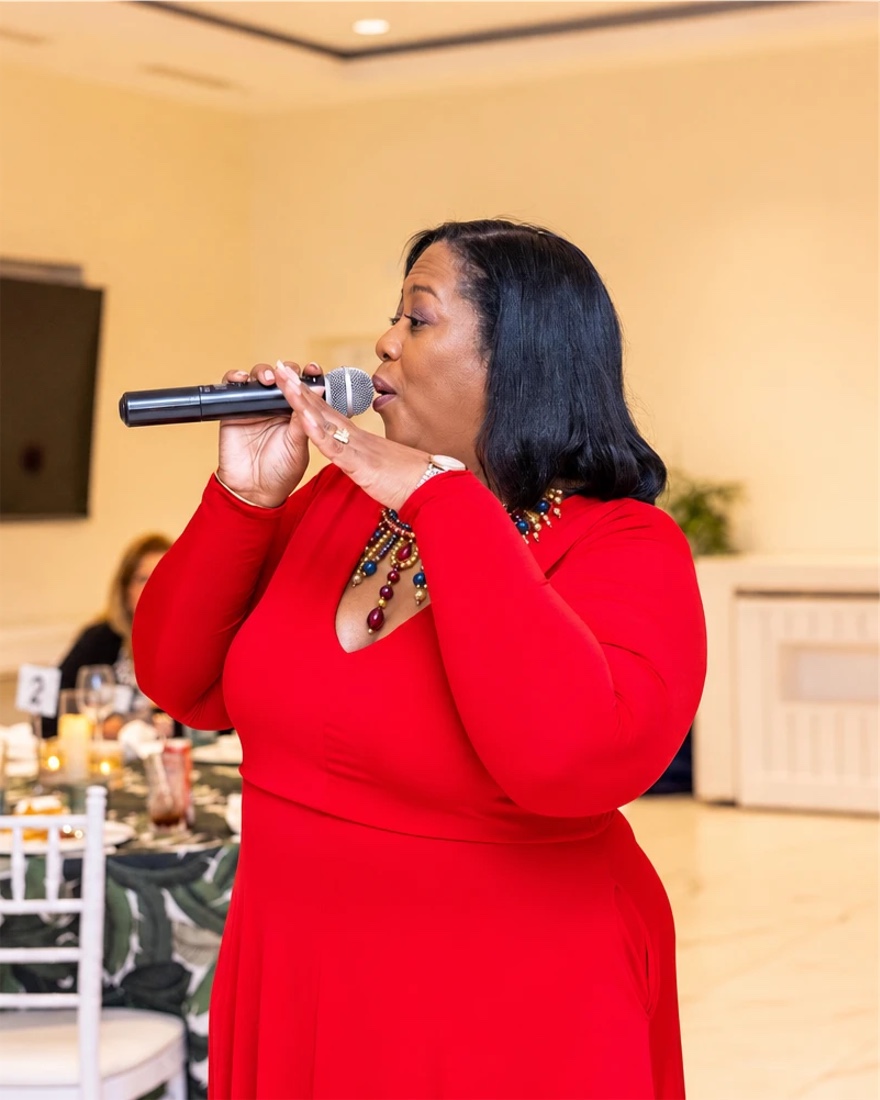 Queen B singing in red at a private dinner