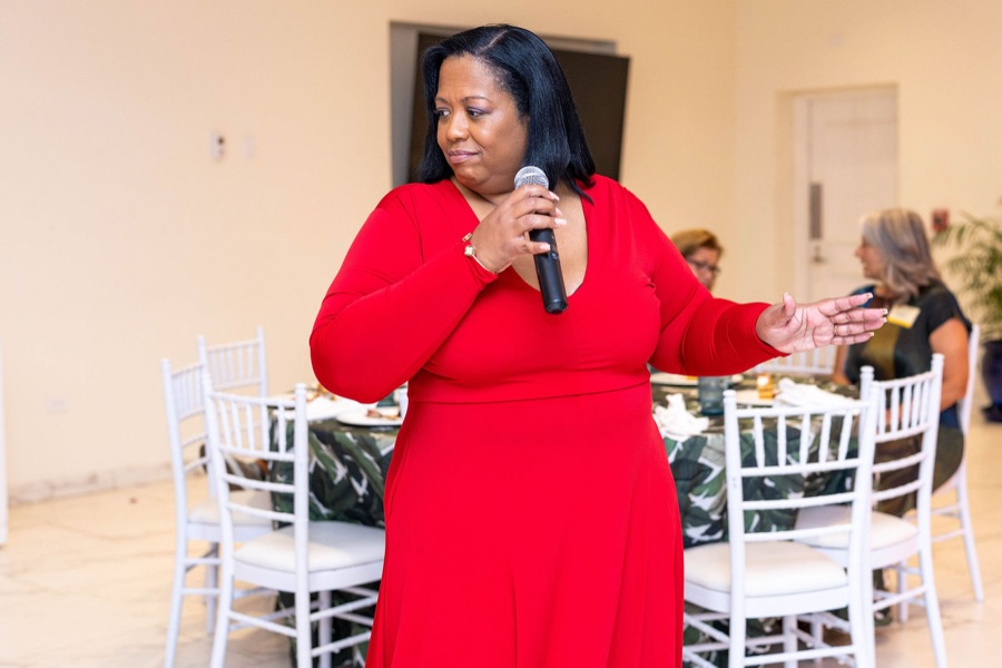 Queen B singing to dinner guests in a red dress